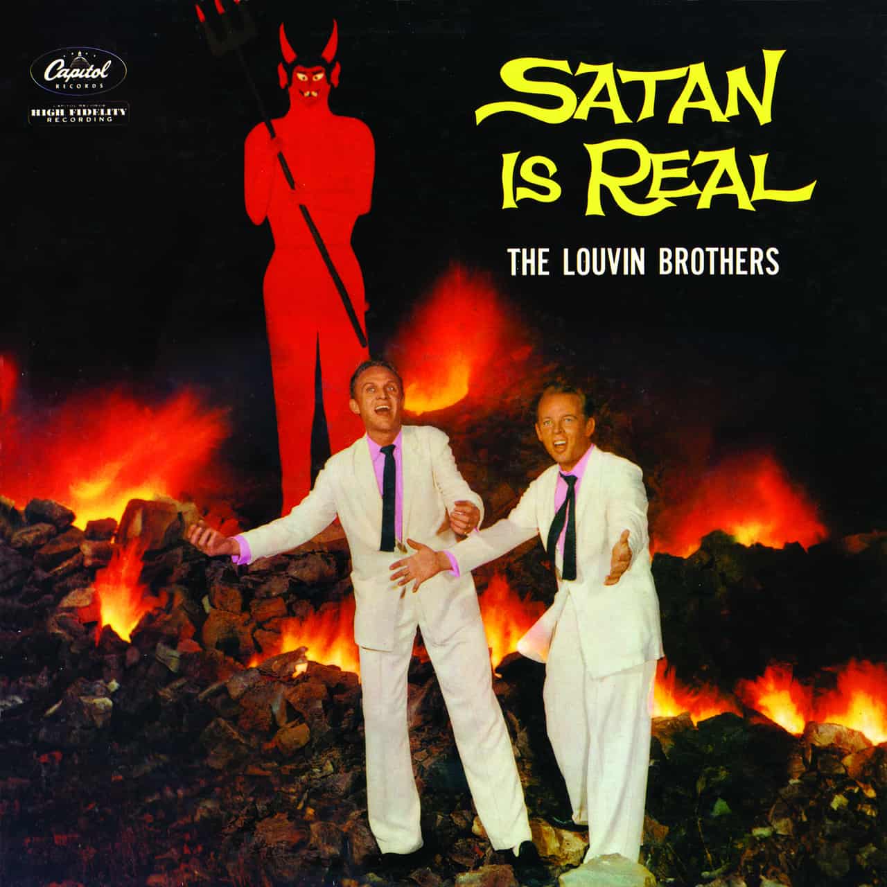 The cover of "Satan is Real" by the Louvin Brothers. The brothers are depicted standing in a fiery rockpile, singing passionately, arms outstretched in front of a crappy cardboard figure of a buck-toothed, pitchfork-holding Satan. The title is pictured in bright yellow, stylized letters.